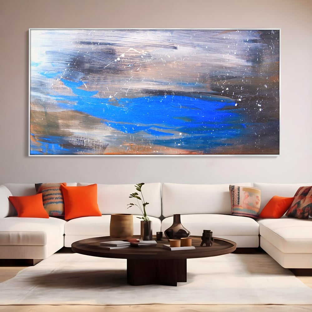 Tablou canvas cu pictura abstracta cu pete albastre, in rama de aluminiu argintiu, pe perete intr-un living